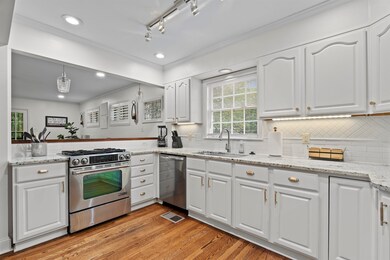 Kitchen with light stone counters, stainless steel appliances, white cabinetry, crown molding, and recessed lighting