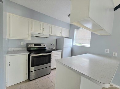 Kitchen featuring stainless steel electric range, under cabinet range hood, freestanding refrigerator, a peninsula, and white cabinetry