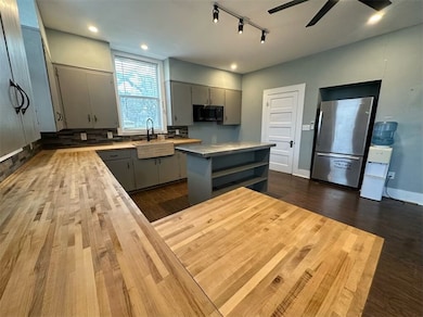 Kitchen with gray cabinetry, dark wood-type floori
