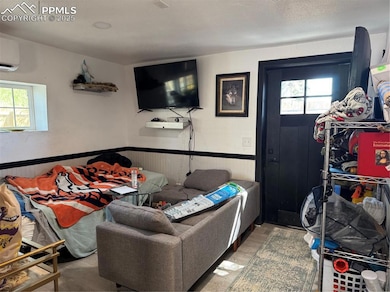 Living area featuring plenty of natural light, wainscoting, and a wall unit AC