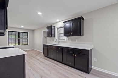 Kitchen with light wood-style floors, light countertops, a sink, baseboards, and recessed lighting