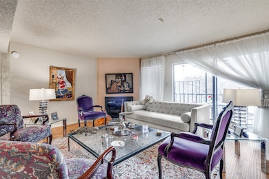Living room with a textured ceiling, wood finished floors, and a glass covered fireplace