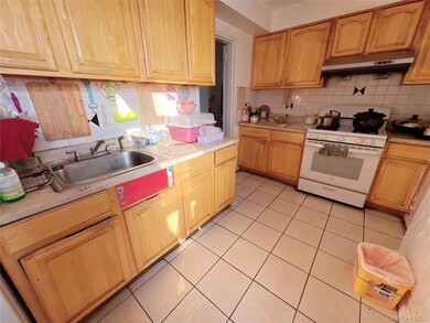 Kitchen featuring gas range gas stove, backsplash, light countertops, light tile patterned floors, and under cabinet range hood