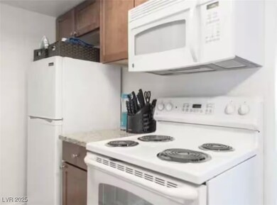 Kitchen featuring white appliances, light countert