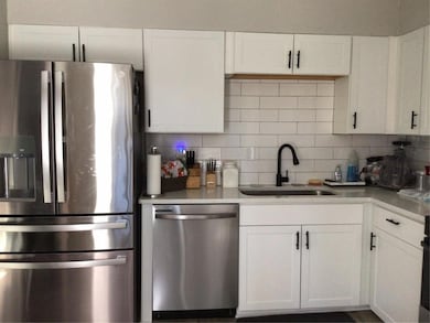 Kitchen featuring decorative backsplash, white cab