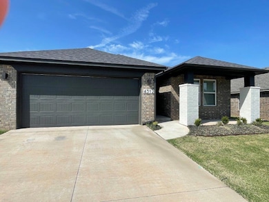 View of front of property with driveway, an attached garage, brick siding, and a shingled roof