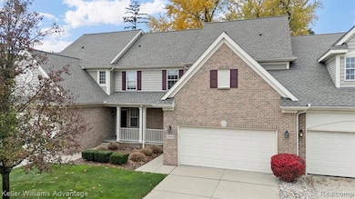 Traditional home with covered porch, a shingled roof, a front lawn, driveway, and brick siding
