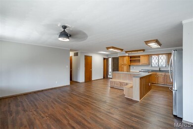 Kitchen with open shelves, dark wood-style flooring, freestanding refrigerator, open floor plan, and ornamental molding