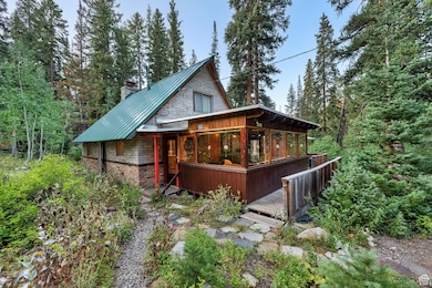 Front view of house featuring a chimney, a deck, a metal roof, a standing seam roof, and a view of trees