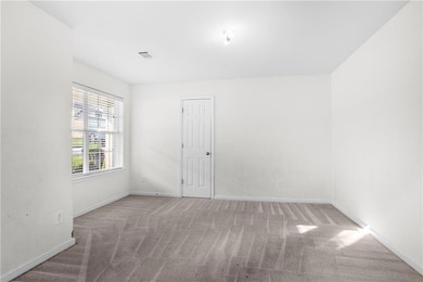 Carpeted empty room featuring stairs and baseboards