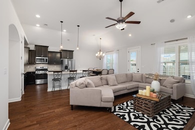 Living room featuring vaulted ceiling, ceiling fan