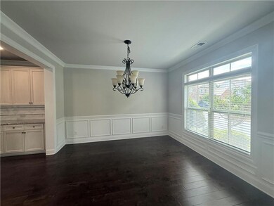 Unfurnished dining area featuring a chandelier, dark wood finished floors, wainscoting, and crown molding