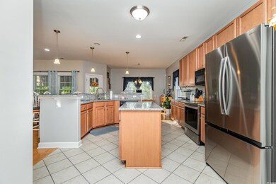 Kitchen with kitchen peninsula, stainless steel appliances, a breakfast bar, light stone countertops, and a center island