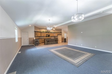 Unfurnished living room featuring lofted ceiling, light colored carpet, a chandelier, and recessed lighting