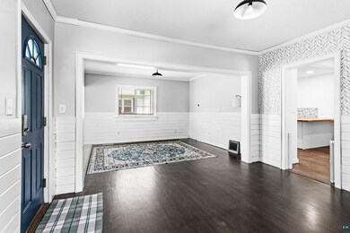 Entryway with crown molding and dark wood-type flo