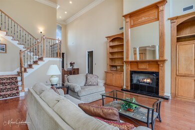 Living room featuring a towering ceiling, wood-type flooring, crown molding, and a tiled fireplace