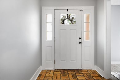 Foyer entrance featuring baseboards and brick floo