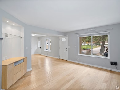 Unfurnished living room featuring light wood-type flooring and baseboards