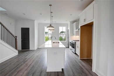 Kitchen featuring stainless steel gas range, exhaust hood, a center island with sink, white cabinetry, and dark wood-type flooring