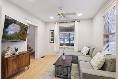 The sun filled living room features modern recessed lighting looking to the sun porch, beautifully cased opening to the dining area and front entry with intricate dovetailed wood floors.