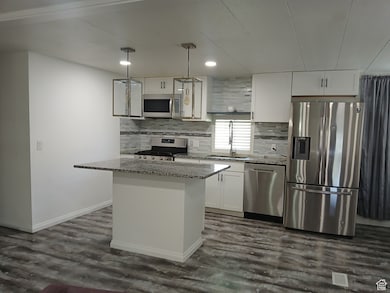 Kitchen featuring light stone countertops, appliances with stainless steel finishes, tasteful backsplash, white cabinetry, and recessed lighting