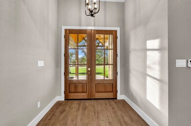 Entryway with a textured wall, wood finished floors, a chandelier, and french doors