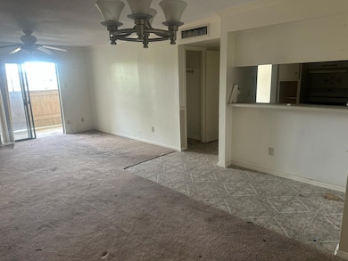 Spacious living area with carpet and tile flooring, ceiling fan, and sliding glass door leading to a small outdoor space. Ideal for customization and natural light.