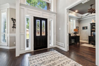 Foyer entrance featuring ornamental molding, dark hardwood / wood-style flooring, ceiling fan, and a raised ceiling