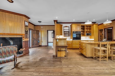 Kitchen with oven, open shelves, ornamental molding, a kitchen breakfast bar, and wood walls