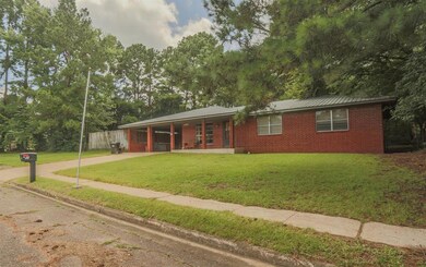 Ranch-style house with concrete driveway, brick siding, a front lawn, an attached carport, and a metal roof