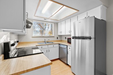 Kitchen with light countertops, stainless steel appliances, light wood-type flooring, white cabinets, and exhaust hood
