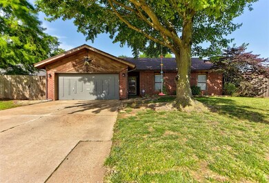 Ranch-style house featuring a garage, concrete driveway, and brick siding