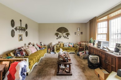 Living room. Original hardwood flooring believed to be under carpet in this room, stairs and bedrooms.