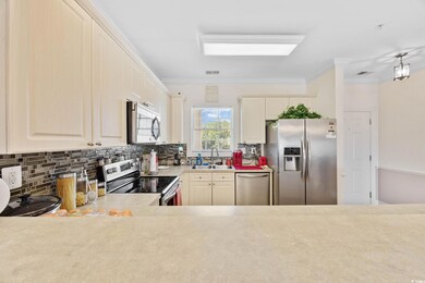 Kitchen featuring stainless steel appliances, tasteful backsplash, light countertops, and ornamental molding