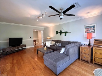 Living room with ornamental molding, wood finished floors, ceiling fan, track lighting, and baseboards