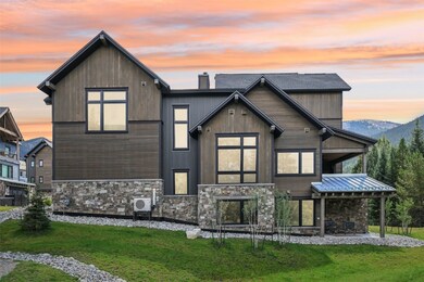 Rear view of property featuring stone siding, a yard, a patio area, and a chimney