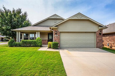 View of front of house with brick siding, concrete driveway, a garage, a front yard, and covered porch