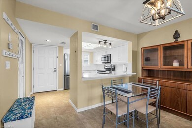 Kitchen with stainless steel appliances, glass insert cabinets, a chandelier, white cabinetry, and light tile patterned floors