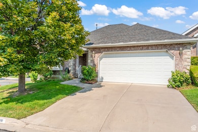View of front of property featuring a shingled roof, brick siding, concrete driveway, a garage, and a front yard