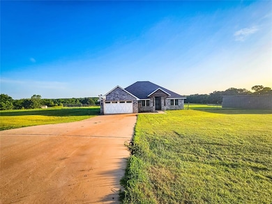 View of front of house featuring stone siding, driveway, a front lawn, and an attached garage