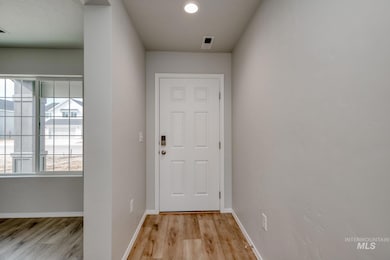 Doorway with light wood-type flooring and baseboards