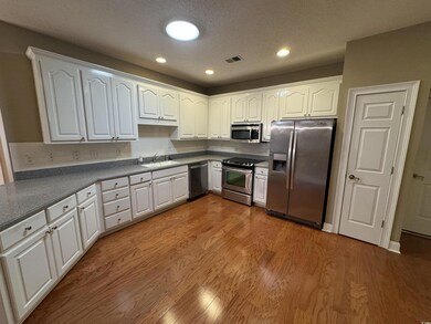 Kitchen with stainless steel appliances, a sink, wood finished floors, white cabinetry, and recessed lighting