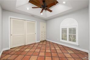 Unfurnished bedroom featuring recessed lighting, a tray ceiling, baseboards, and a closet