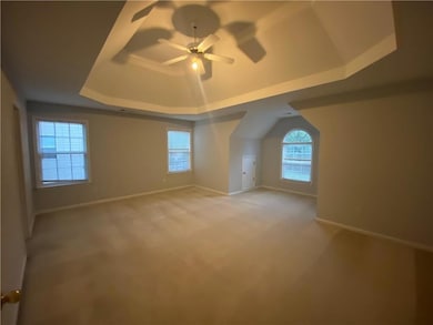 Spare room with a raised ceiling, a ceiling fan, and light colored carpet