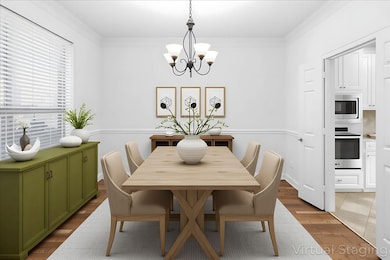 Virtual photo. Dining space featuring ornamental molding, wood finished floors, and a chandelier