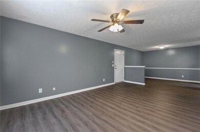 Empty room featuring wood finished floors, a ceiling fan, and a textured ceiling