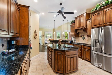 Kitchen with tasteful backsplash, a kitchen island, ceiling fan, appliances with stainless steel finishes, and pendant lighting