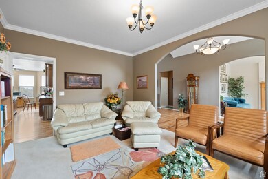 Living area featuring arched walkways, a chandelier, crown molding, and wood finished floors
