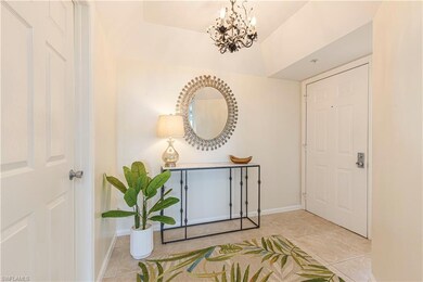 Tiled entryway featuring a chandelier and vaulted ceiling
