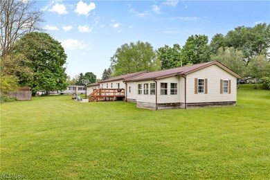 Back of house featuring a lawn and a deck